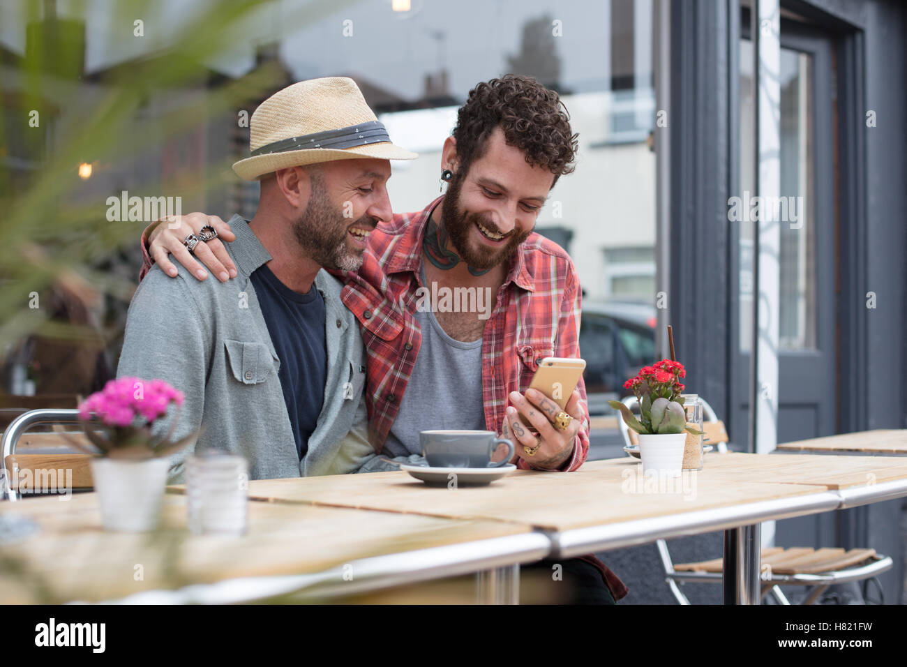 Coppia gay condivisione sat telefono in cafe Foto Stock