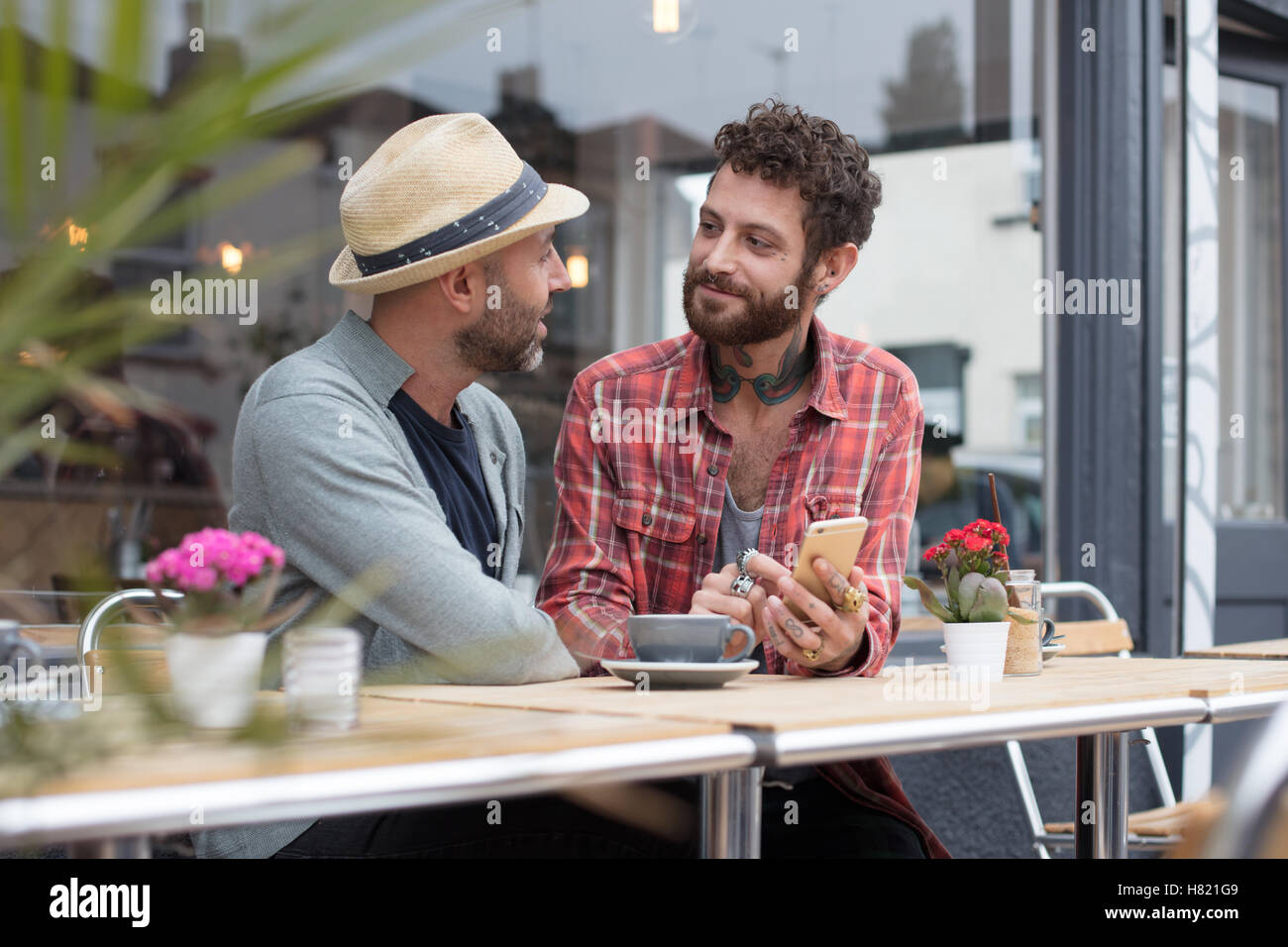 Coppia gay telefono condivisione in cafe Foto Stock