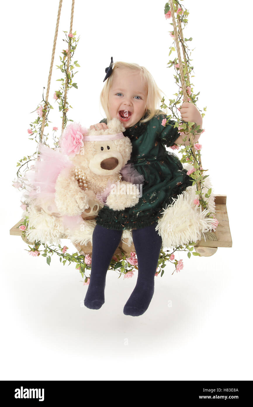 Baby girl su studio fotografico swing con fiori e teddy Foto Stock