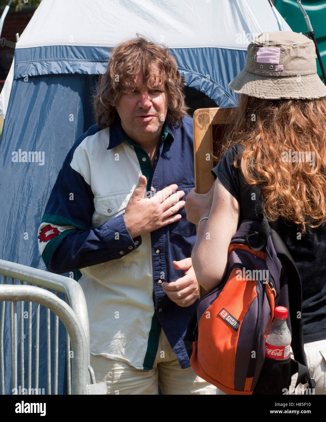 Uomo al festival di musica cerca su una camicia mentre la sua ragazza detiene uno specchio Foto Stock