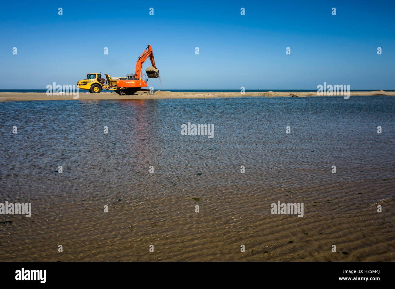 Scavi di scavo di sabbia su un tratto di spiaggia che è poi trasportato in un altra zona di conservazione di Langeoog la linea costiera e proteggere l'ambiente. Foto Stock