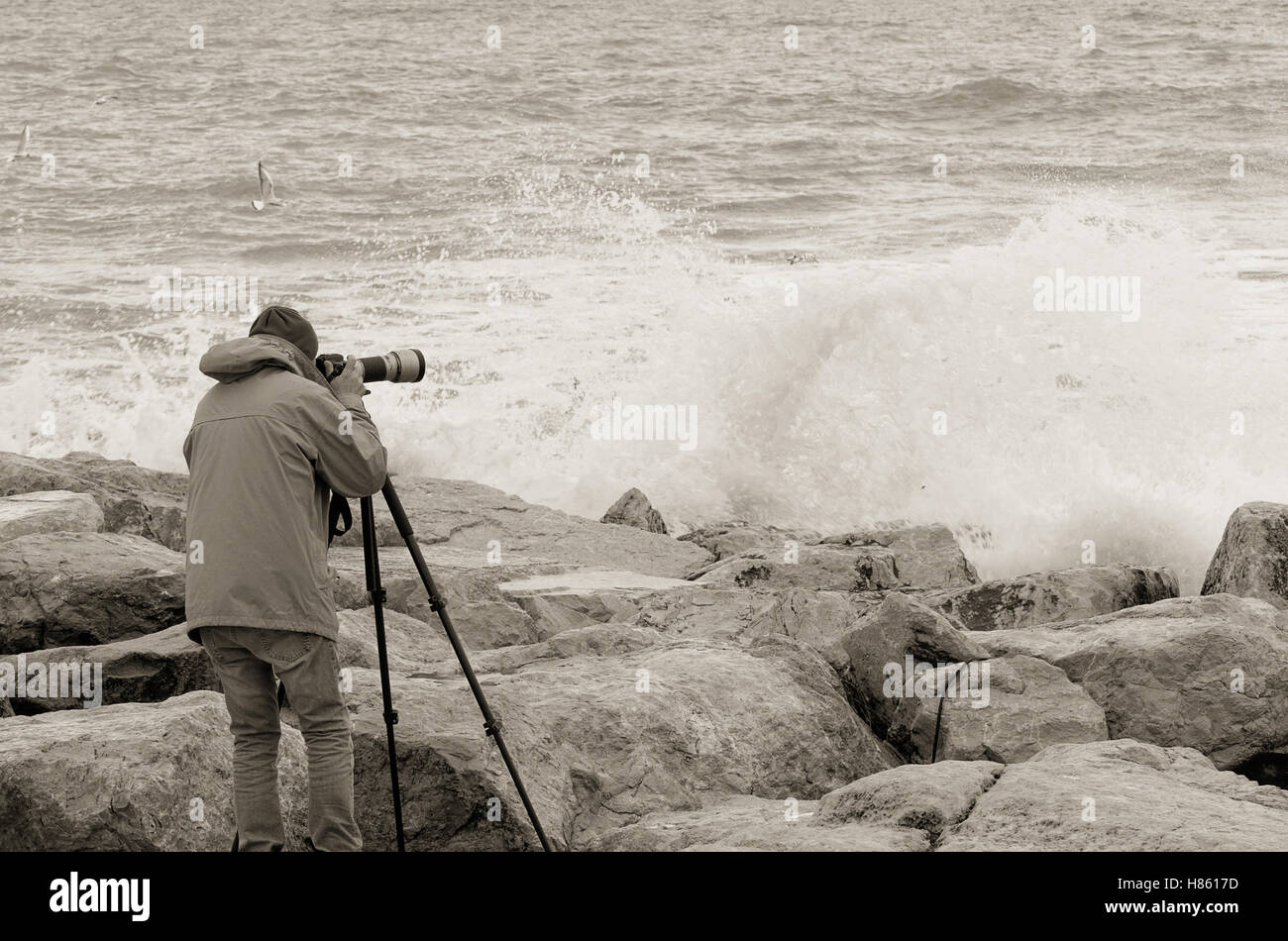 Fotografo oltre la scogliera con mare tempestoso Foto Stock