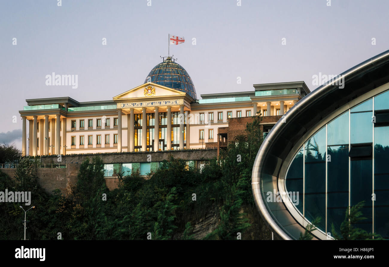 Parte della sala da concerto contro la residenza ufficiale del presidente georgiano di Tbilisi con illuminazione nel crepuscolo, Georgia Foto Stock