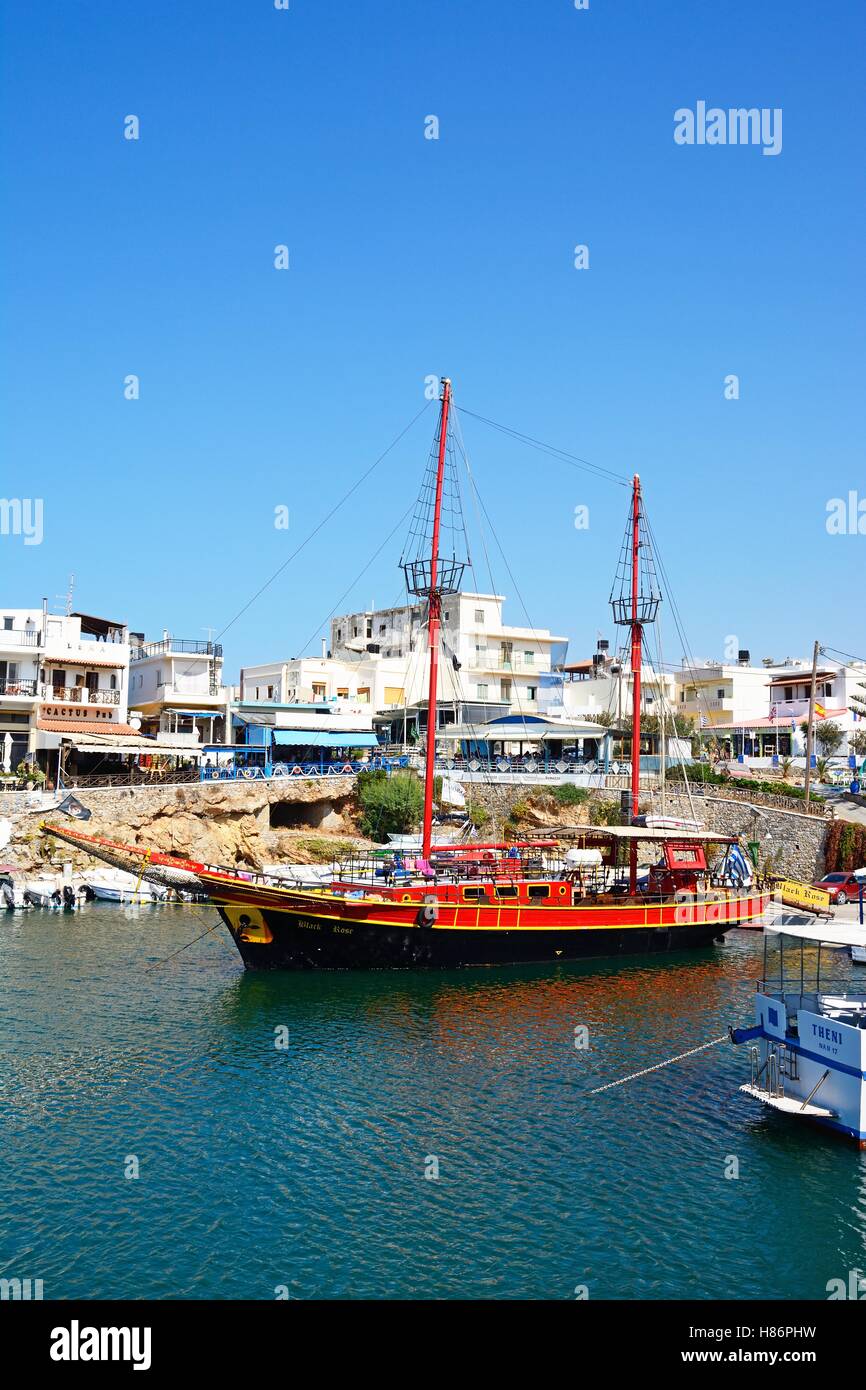 Rosa nero la nave dei pirati ormeggiata in porto con ristoranti sul lungomare verso la parte posteriore, Sissi, Creta, Grecia, l'Europa. Foto Stock