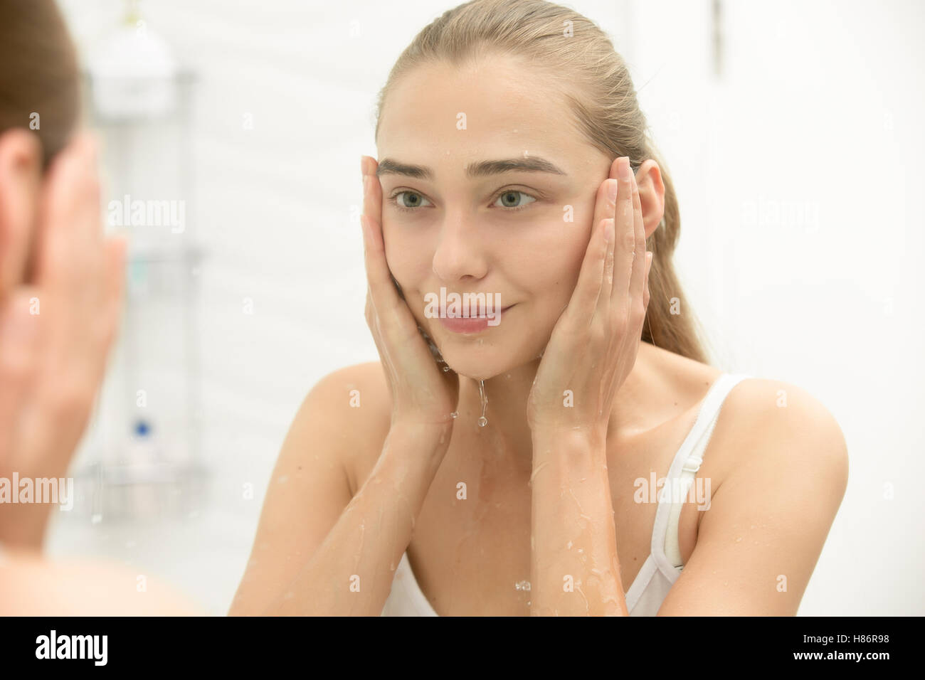 Giovane ragazza dopo il lavaggio la sua faccia acqua vicino al lavandino Foto Stock