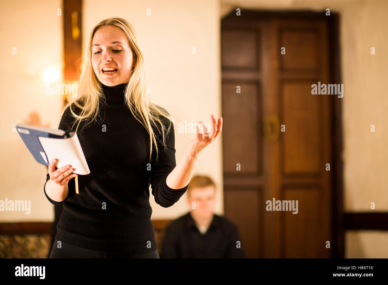 Un giovane attore femmina pianura indossando il costume nero e tenendo premuto il suo script di eseguire gli estratti da Shakespeare e riproduce la poesia in un piccolo teatro scala spazio sopra un pub in Aberystwyth Wales UK Foto Stock