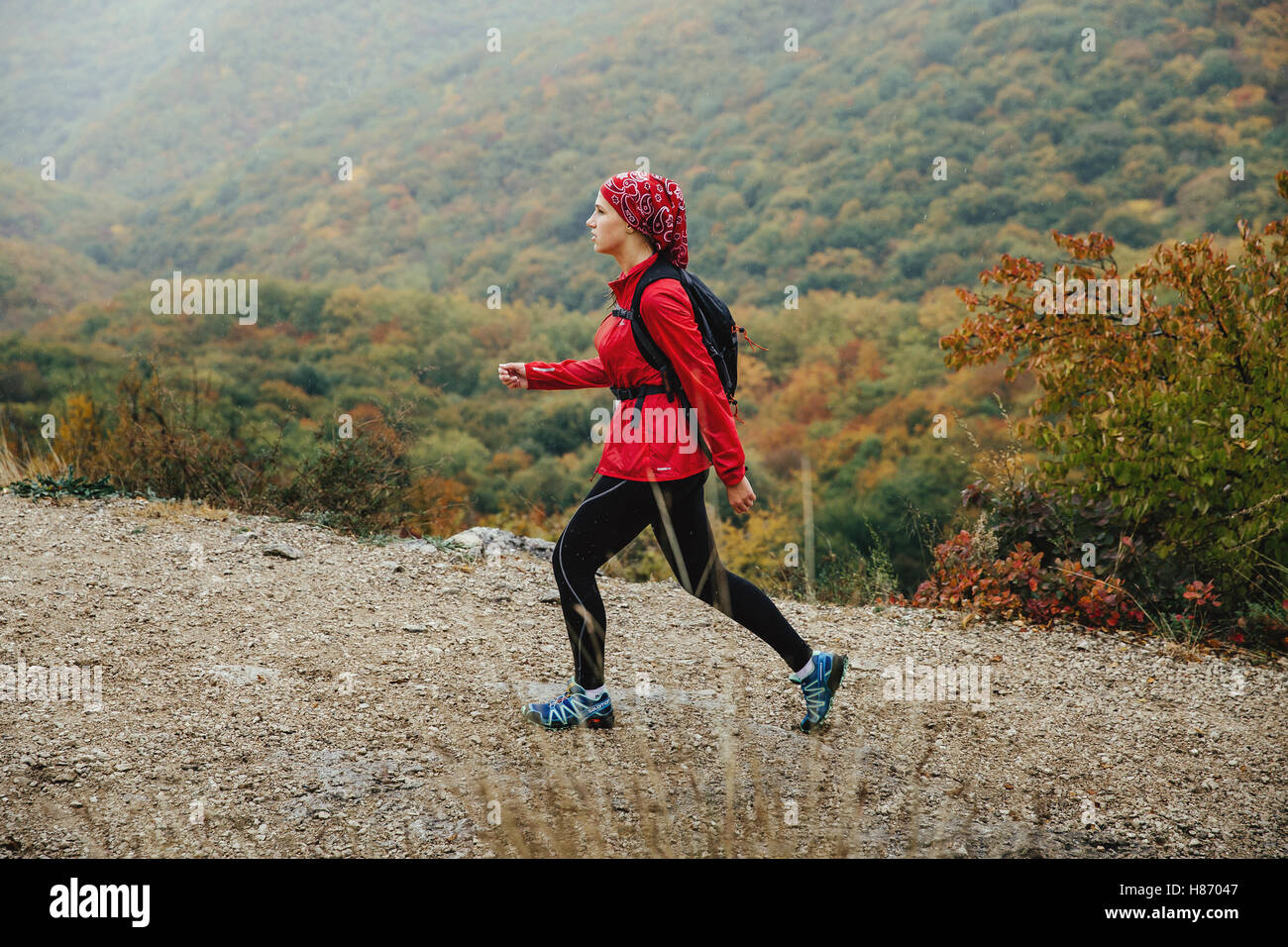 Ragazza giovane turista in viaggio su un sentiero di montagna a piedi sotto la pioggia durante la Crimea maratona di montagna Foto Stock