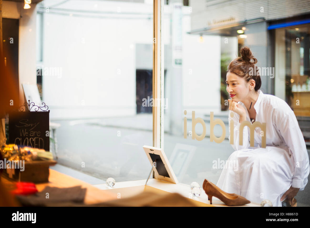 La donna lavora in una boutique alla moda di Tokyo, Giappone, guardando alla finestra di visualizzazione. Foto Stock