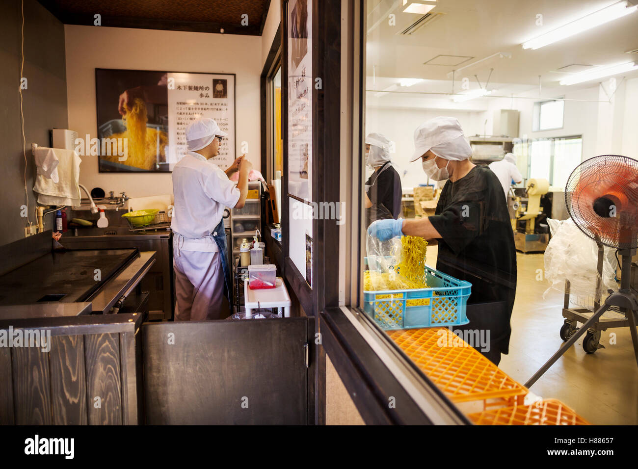 La produzione di fabbrica unità commerciali e cucina che serve un noodle shop. La gente che lavora e uno chef in una stufa. Foto Stock