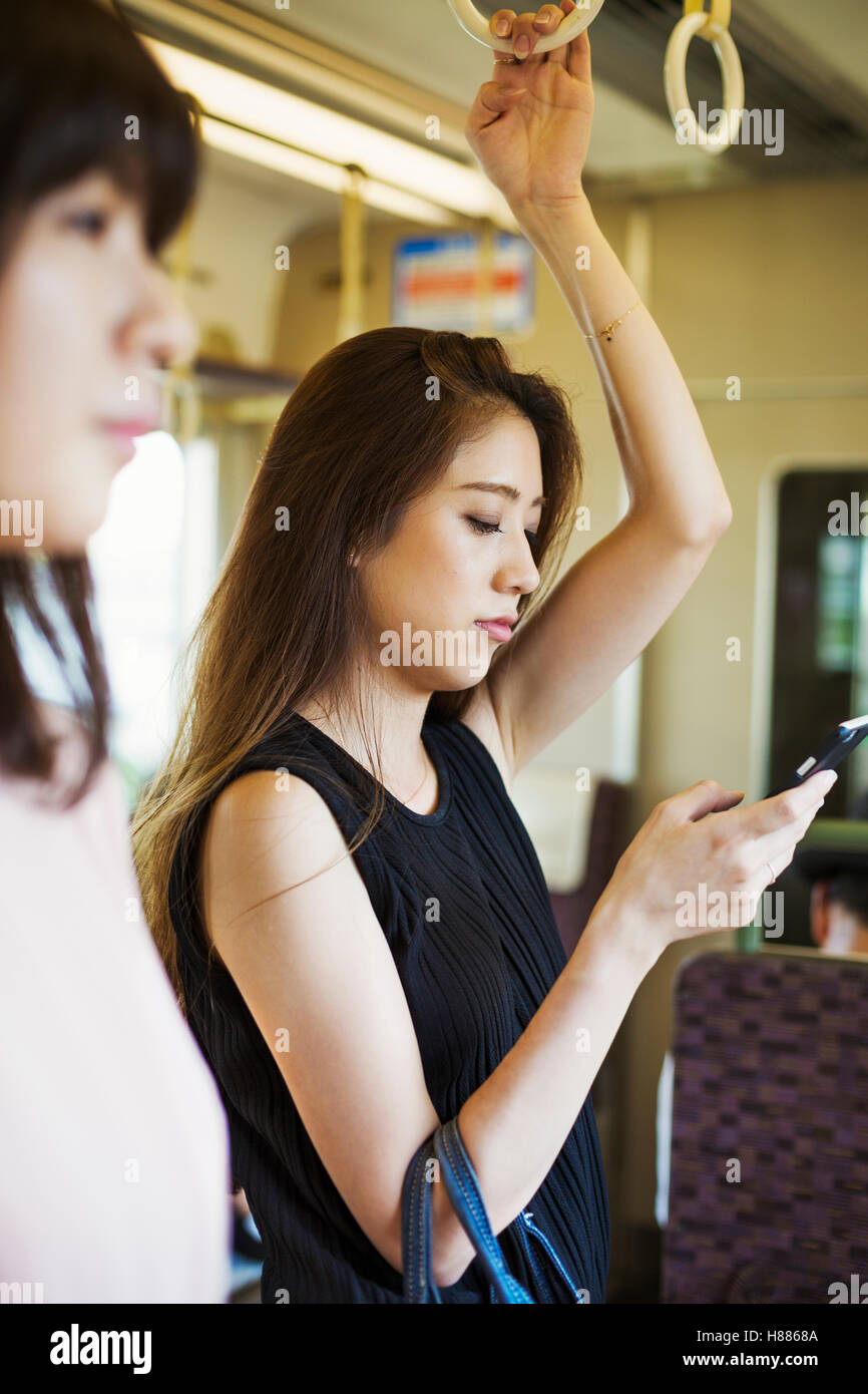 Donna con capelli lunghi marrone viaggiare sui mezzi di trasporto pubblici, utilizzando il telefono cellulare. Foto Stock