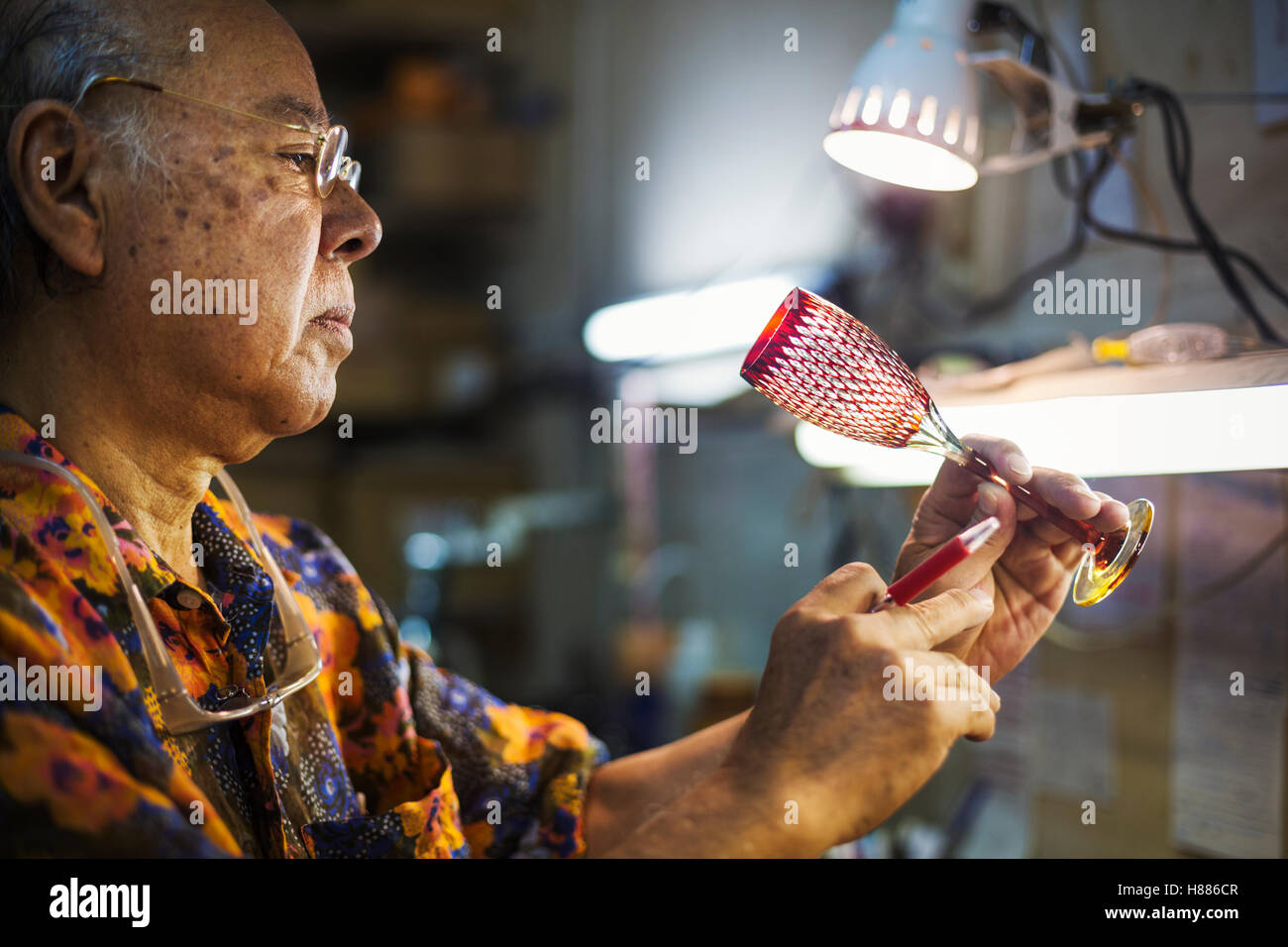 Un senior artigiano al lavoro in un vetro maker's studio workshop. Foto Stock