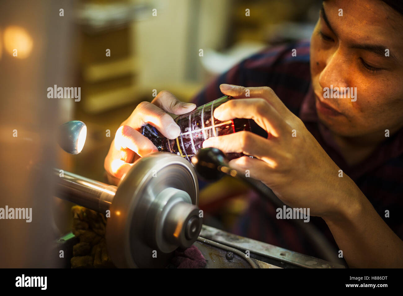 Un artigiano al lavoro presso una macchina, incisione o rigature un vetro colorato oggetto. Foto Stock