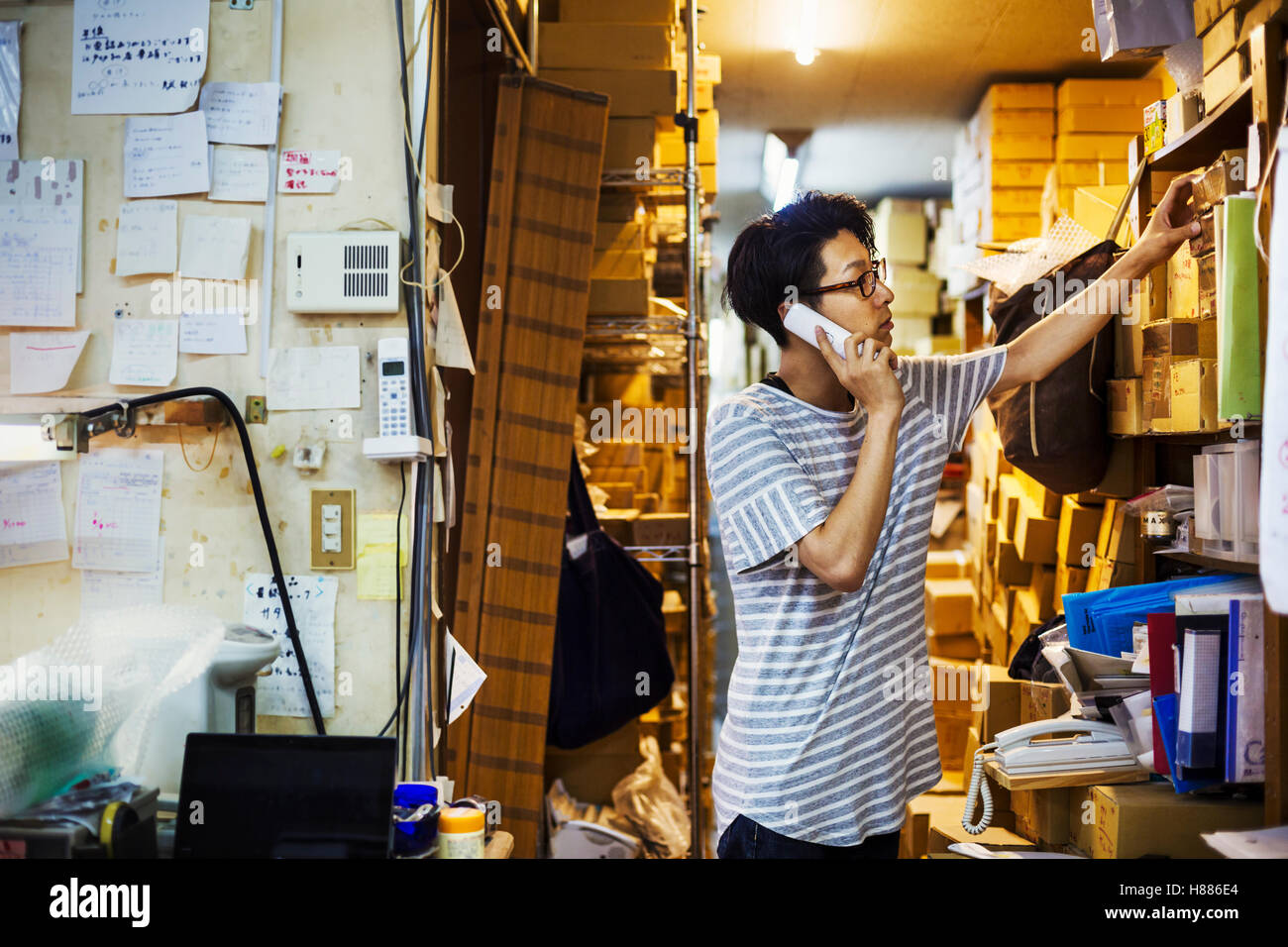 Un uomo al lavoro in un vetro maker's studio workshop sul telefono. Foto Stock