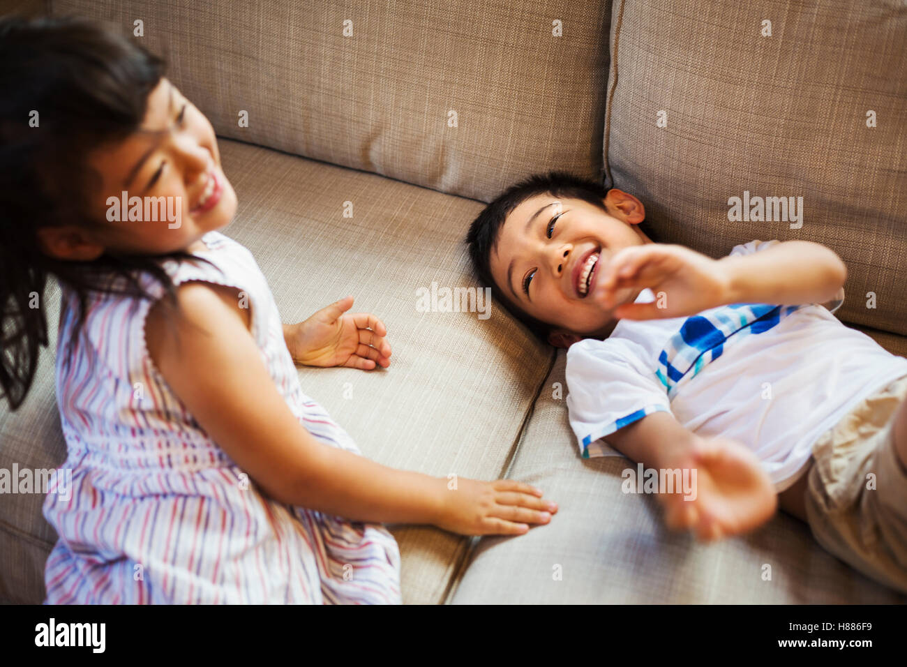 Casa di famiglia. Due bambini che giocano sul pavimento, sogghignando. Foto Stock