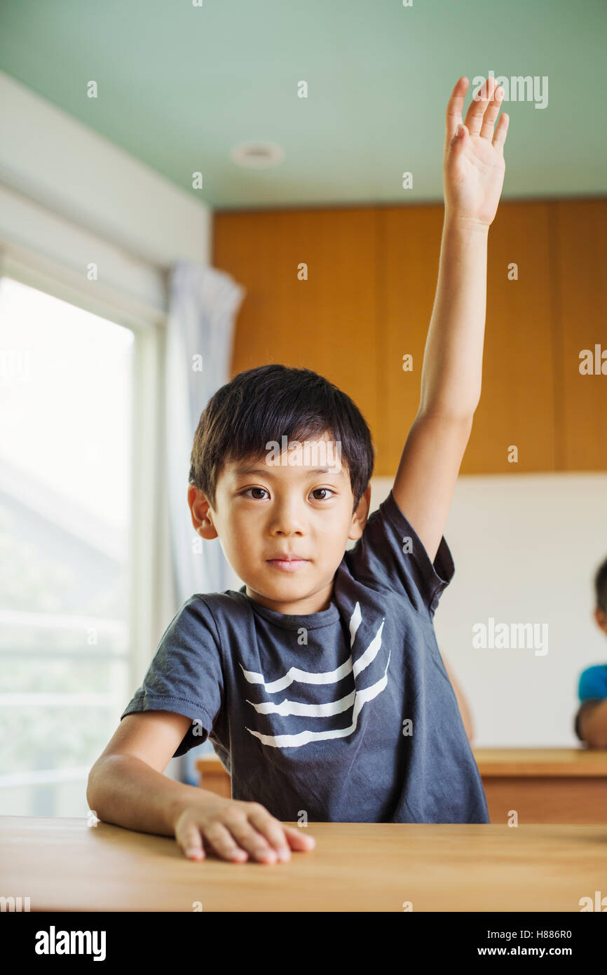 Un ragazzo con la sua mano pronto a rispondere a una domanda. Foto Stock