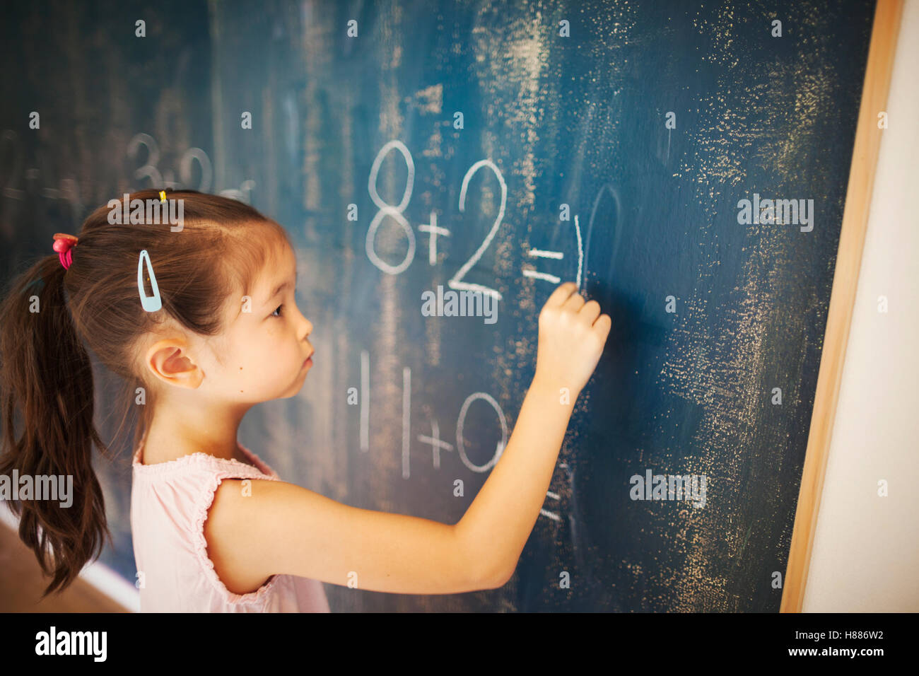 Una ragazza di scrittura in gesso su una lavagna nella scuola. Foto Stock