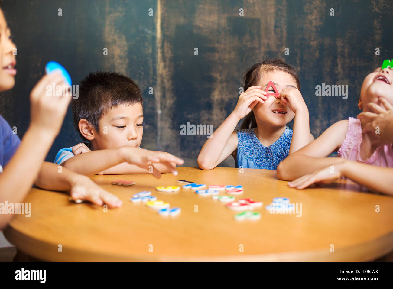 Un gruppo di bambini nella scuola. Due ragazzi e due ragazze tenendo in mano le lettere dell'alfabeto. Foto Stock