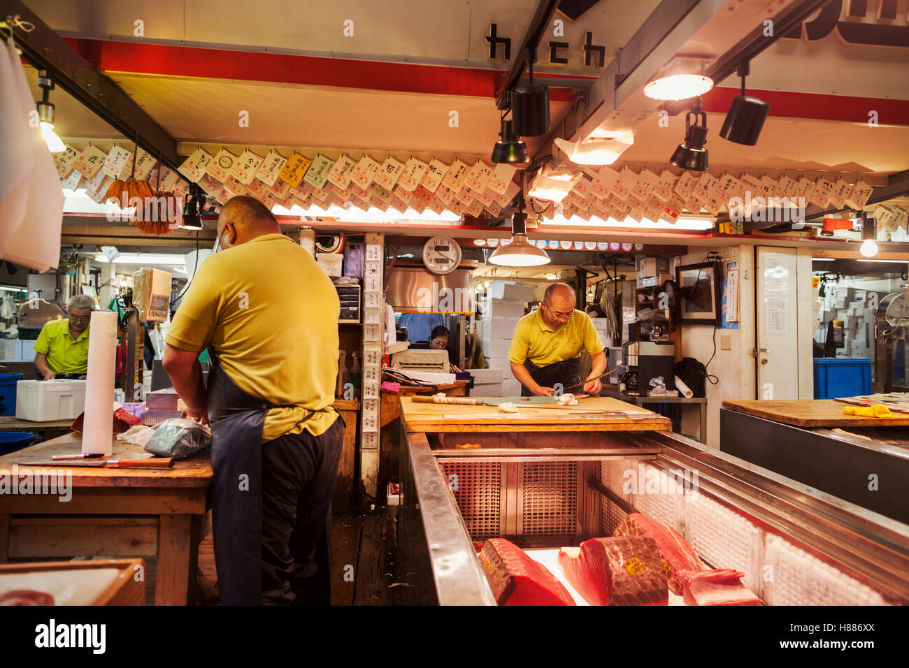 Un tradizionale mercato del pesce fresco in Tokyo. Un pescivendolo lavora la sfilettatura un grande pesce su una lastra. Persone in background. Foto Stock