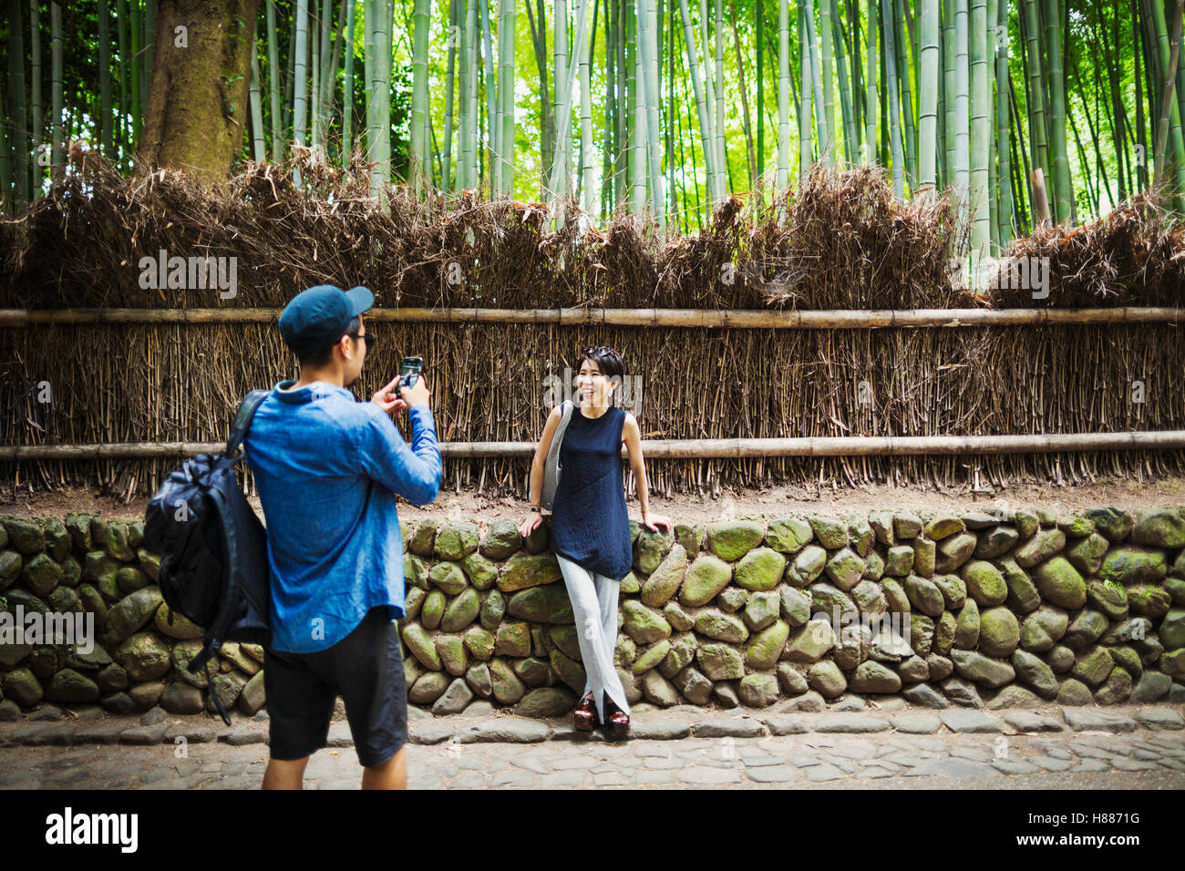 Un uomo di fotografare una donna da una recinzione intorno al bosco. Foto Stock