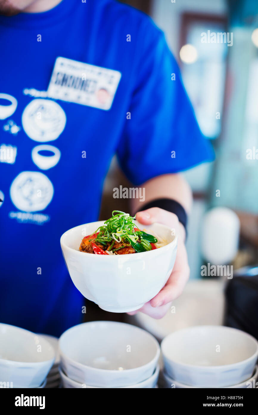 Il ramen noodle shop. Uno chef che prepara una ciotola di carni di spaghetti ramen con carne e verdure. Foto Stock