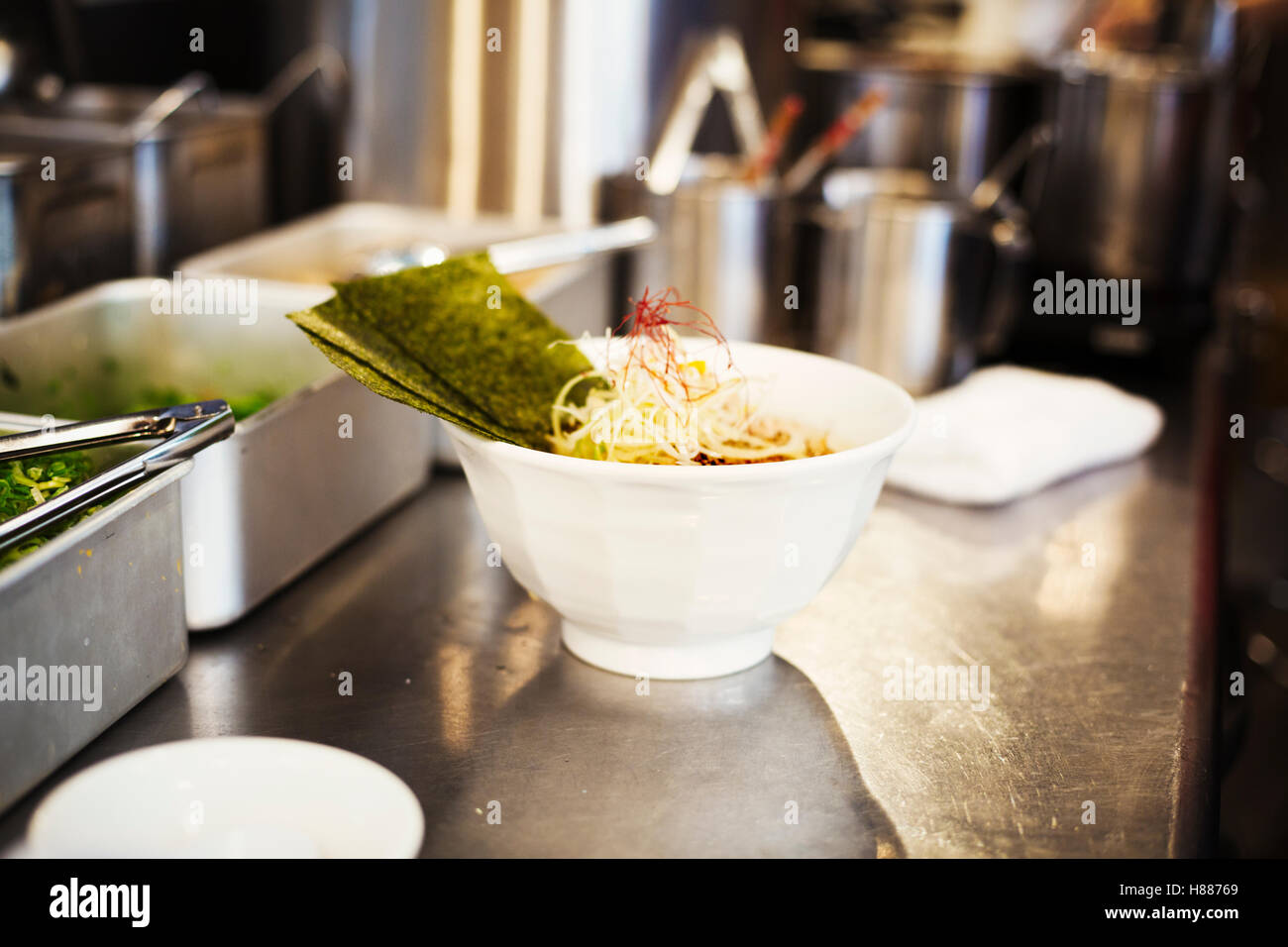 Un ramen noodle shop cucina. Uno chef che prepara le ciotole di spaghetti ramen in brodo, una specialità e fast food piatto. Foto Stock