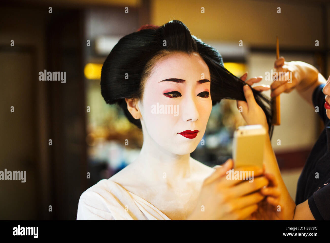 Una moderna geisha maiko o donna è preparata in modo tradizionale, con faccia bianca del trucco. Foto Stock