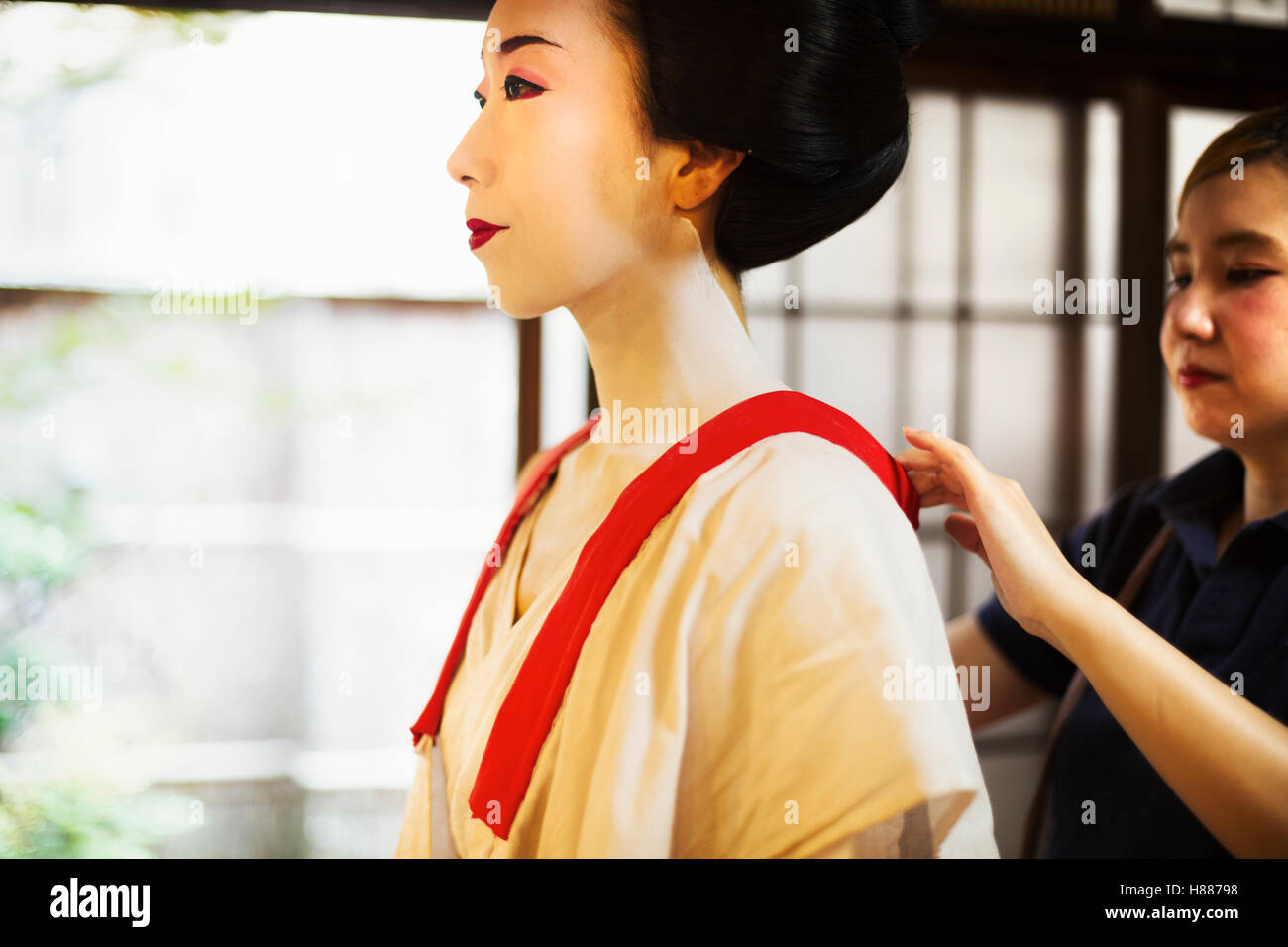 Una moderna geisha maiko o la donna è vestita in modo tradizionale in un cambio di colore bianco con il collare allentato, con faccia bianca del trucco. Foto Stock
