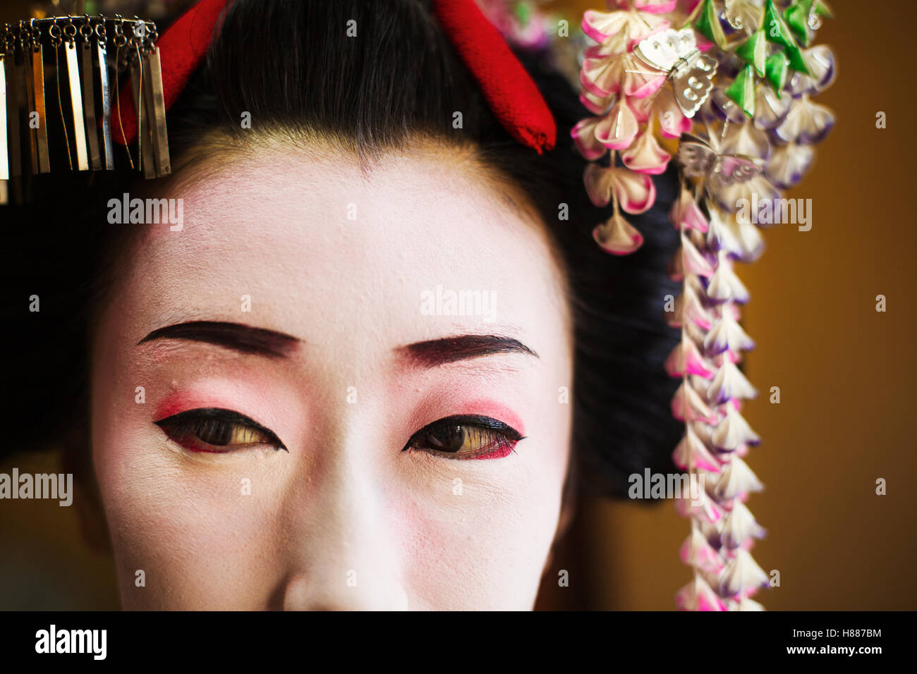 Una donna composta in tradizionale stile geisha con una elaborata acconciatura e floreali clip per capelli Foto Stock