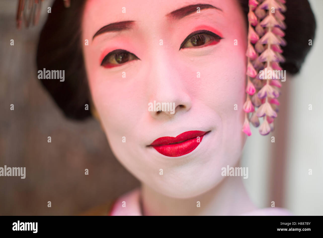 Una donna composta in tradizionale stile geisha con una elaborata acconciatura e floreali clip per capelli Foto Stock