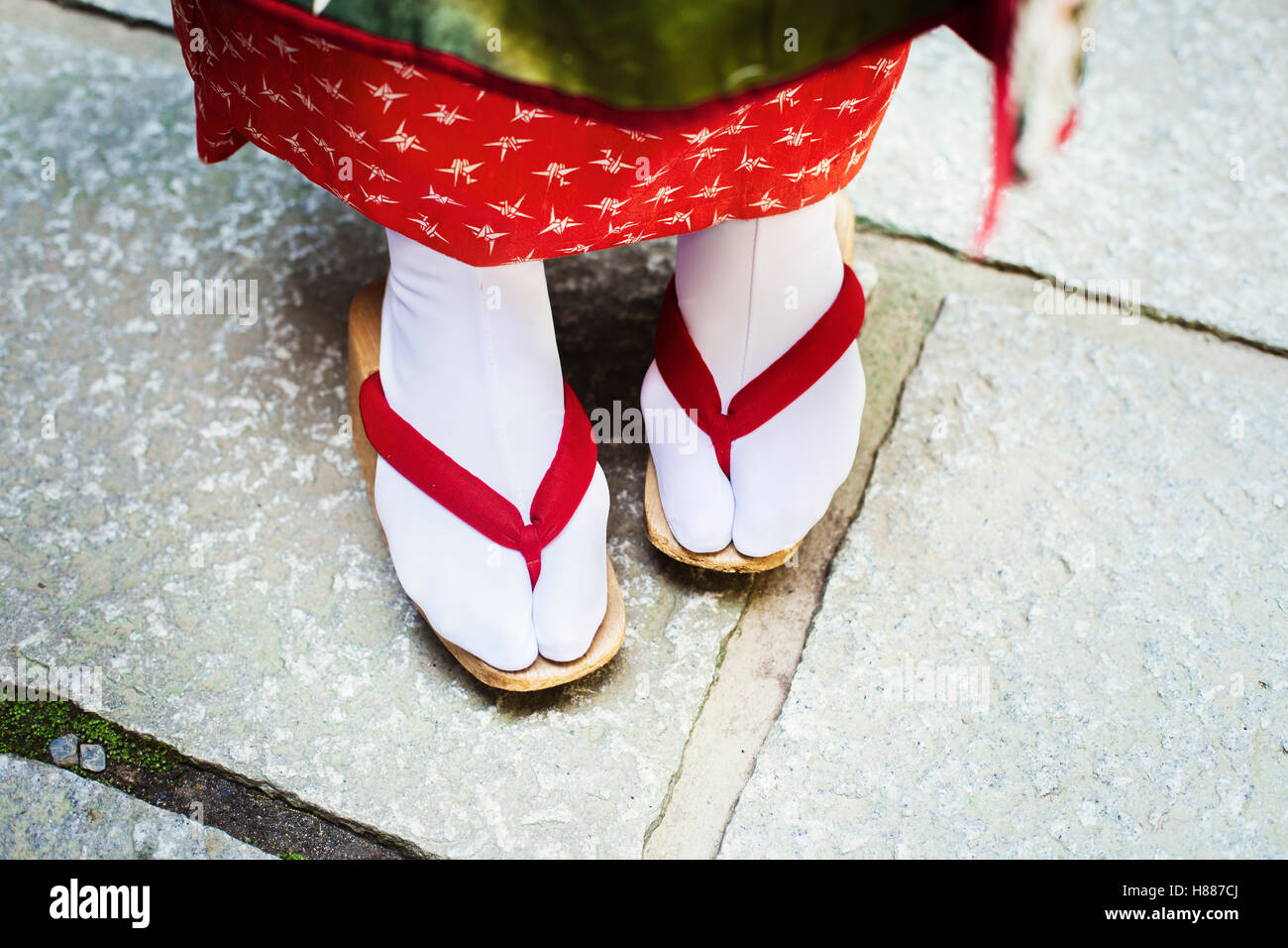 Un tradizionale geisha donna, piedi in legno sandali con suole, con  fascette di rosso e calze bianche o dei tabi Foto stock - Alamy
