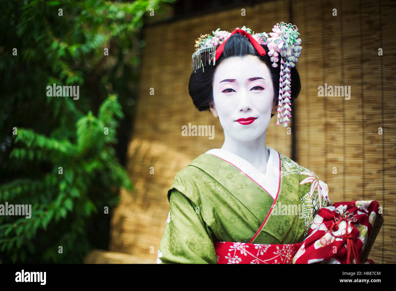 Una Donna vestita con il tradizionale stile geisha, indossando un kimono e OBI, con faccia bianca del trucco. Foto Stock