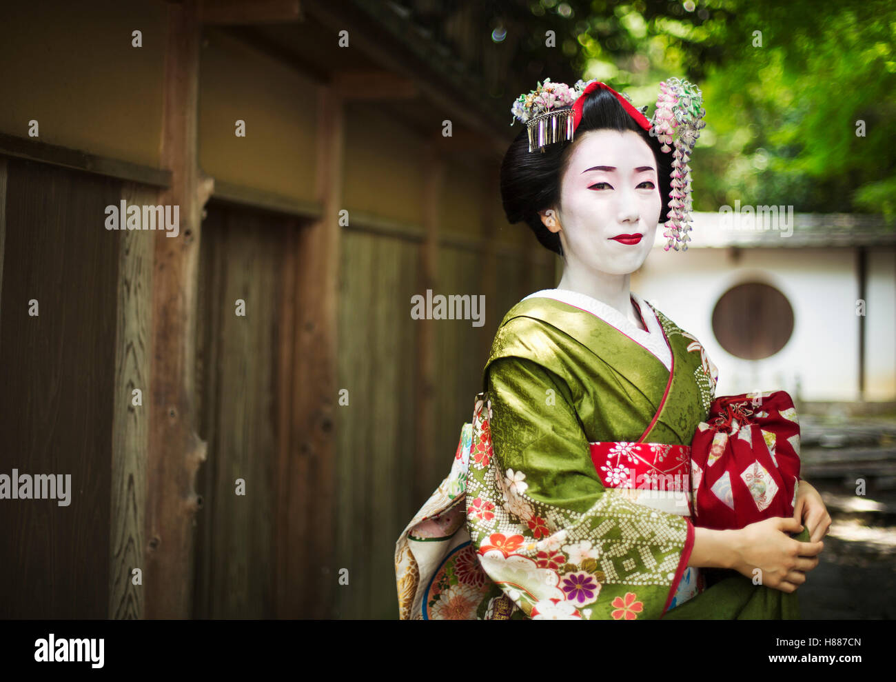 Una Donna vestita con il tradizionale stile geisha, indossando un kimono e OBI, con faccia bianca del trucco. Foto Stock
