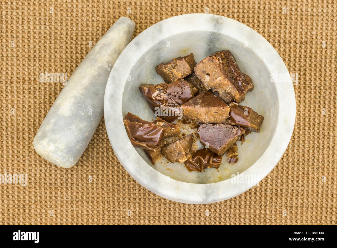Torta Asafoetida pezzi nel mortaio in marmo sul tappetino di iuta Foto Stock
