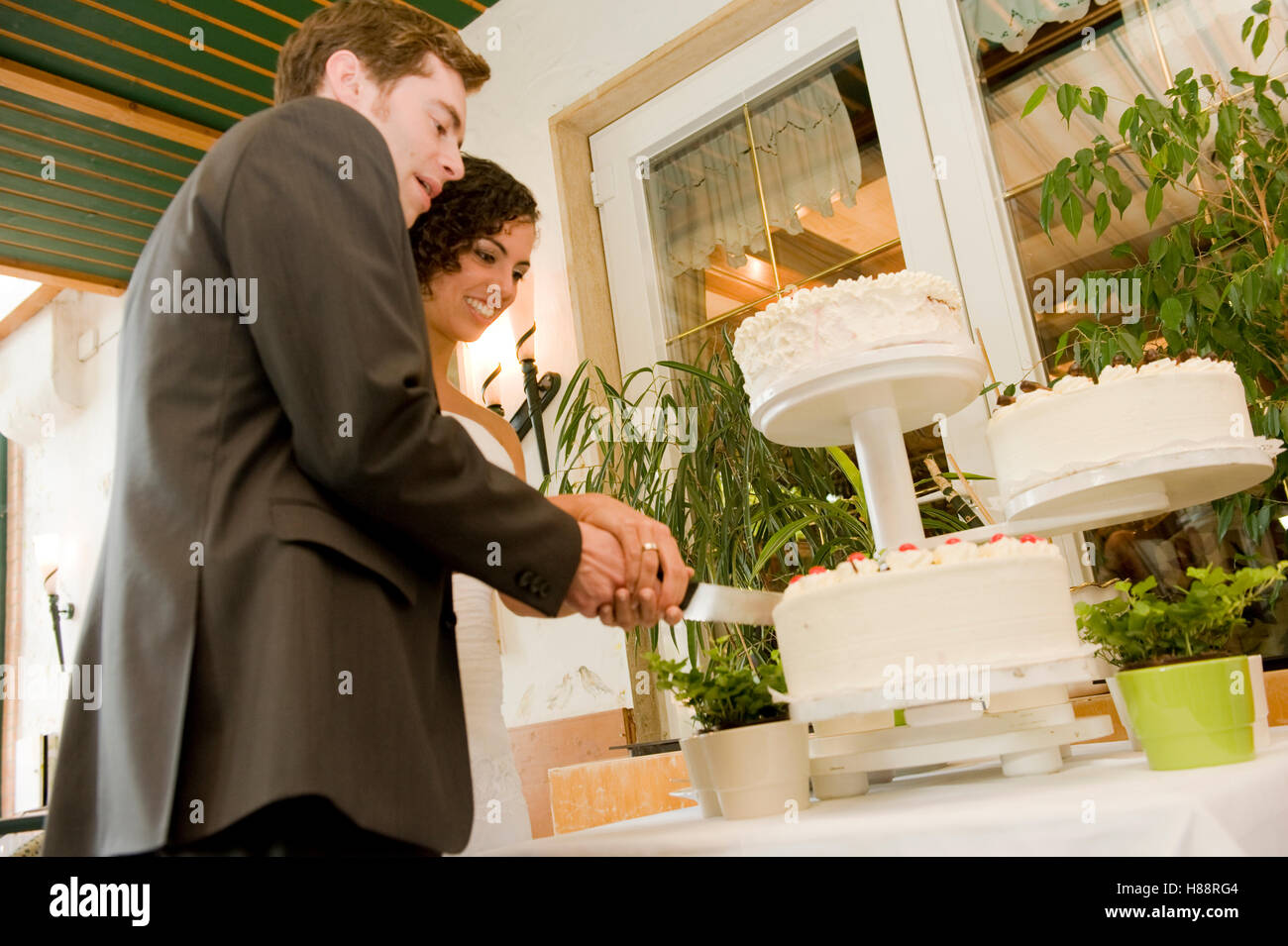 Coppie in viaggio di nozze il loro taglio torta nuziale Foto Stock