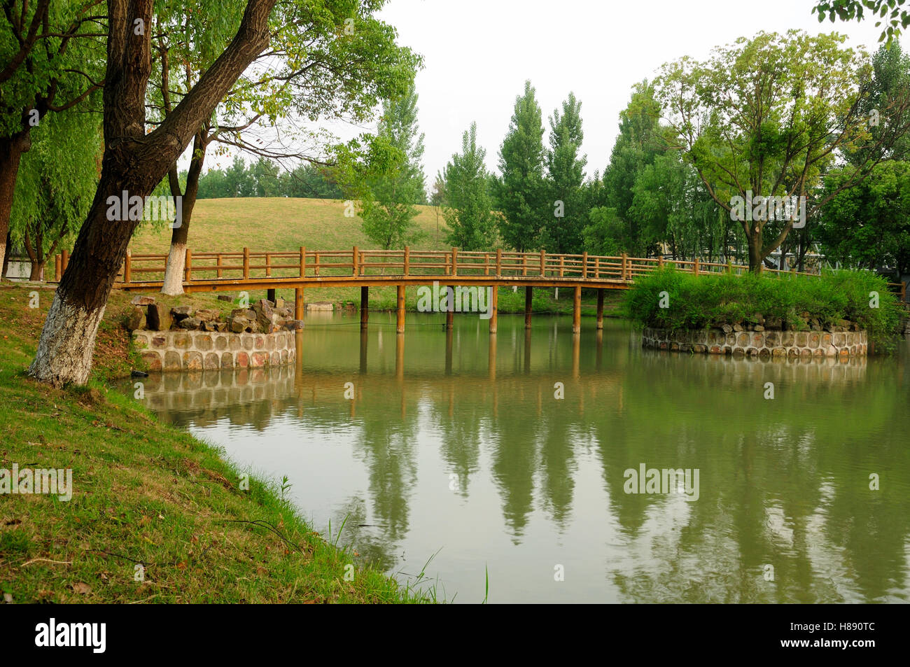 Un ponte di legno attraversando un piccolo lago artificiale entro i tre regni scenic area di wuxi, Cina nella provincia di Jiangsu. Foto Stock