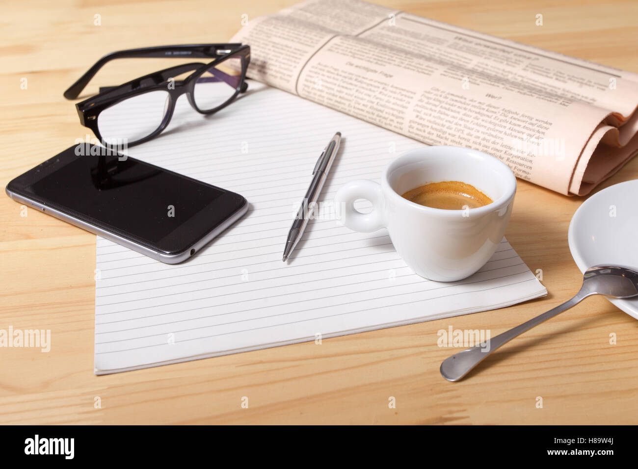 Quotidiani e la tazza di caffè, gli occhiali da lettura, penna e carta a righe. Foto Stock