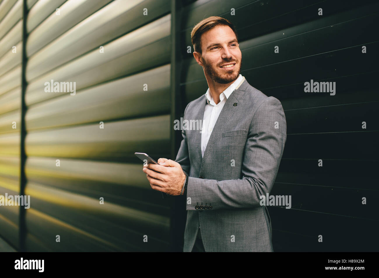 Imprenditore con un telefono dal muro nero Foto Stock