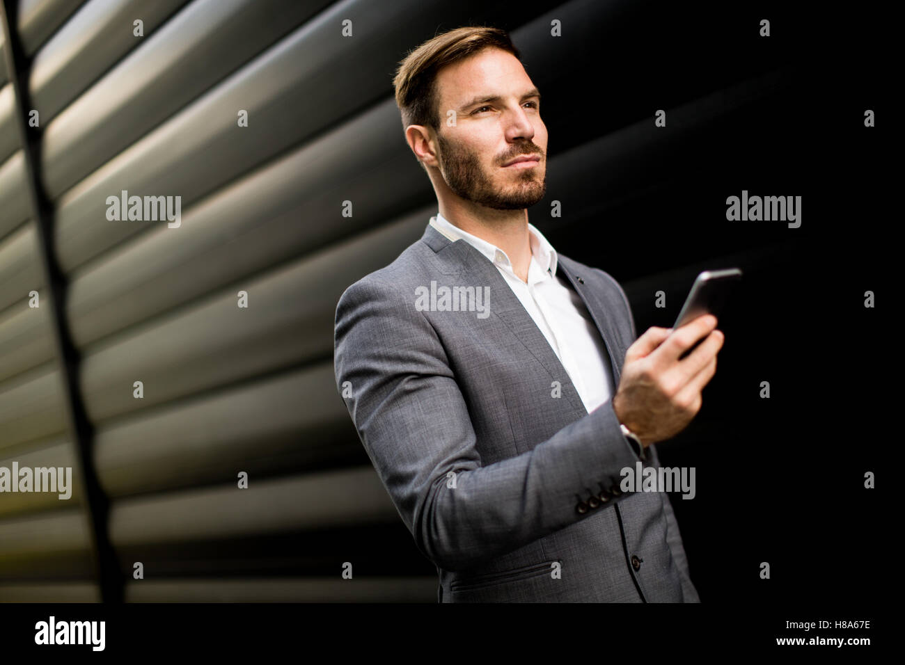 Imprenditore con un telefono dal muro nero Foto Stock