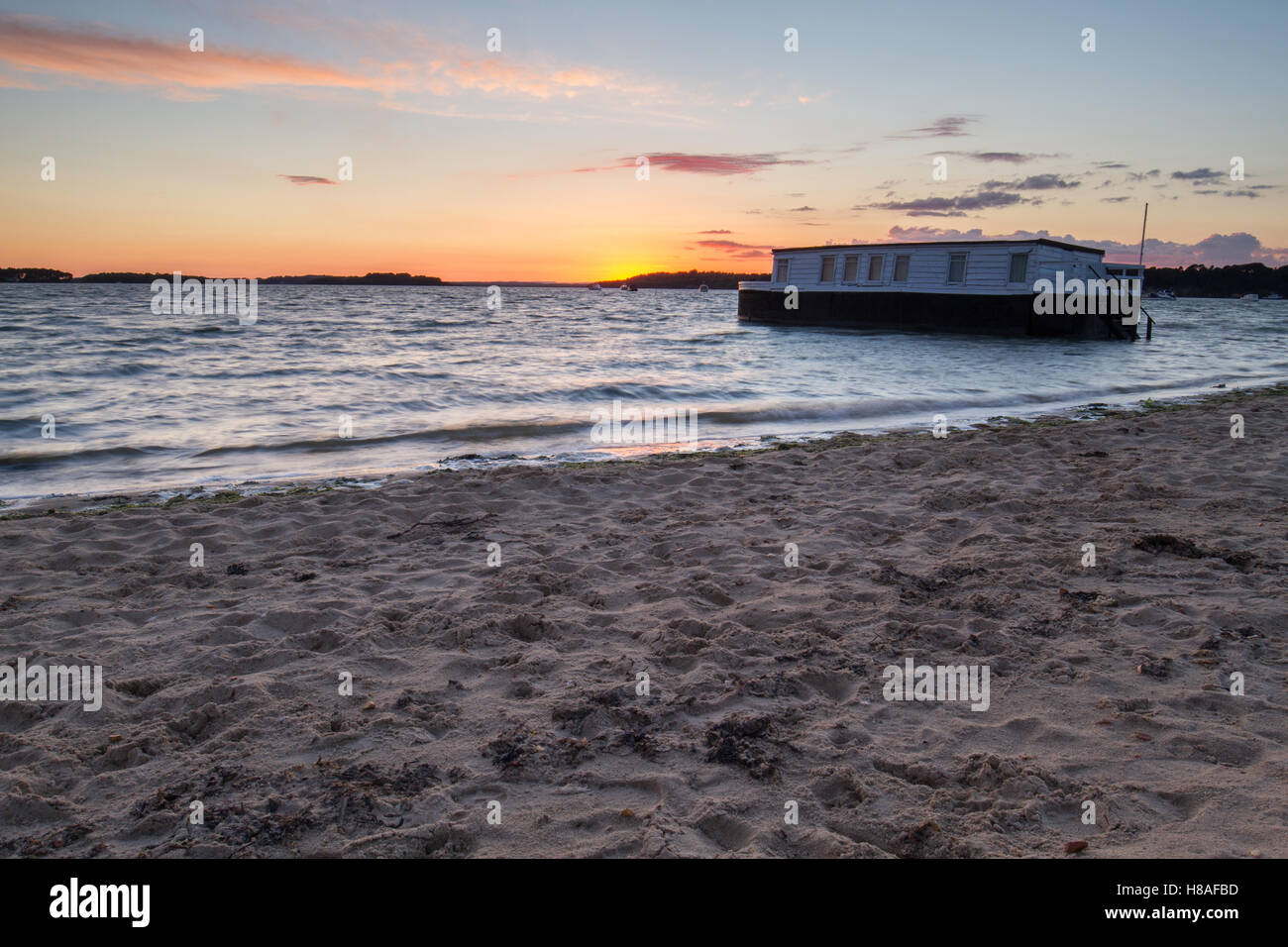 Piuttosto il tramonto la lappatura vacillare nella baia con houseboat e nuvole nel cielo Foto Stock