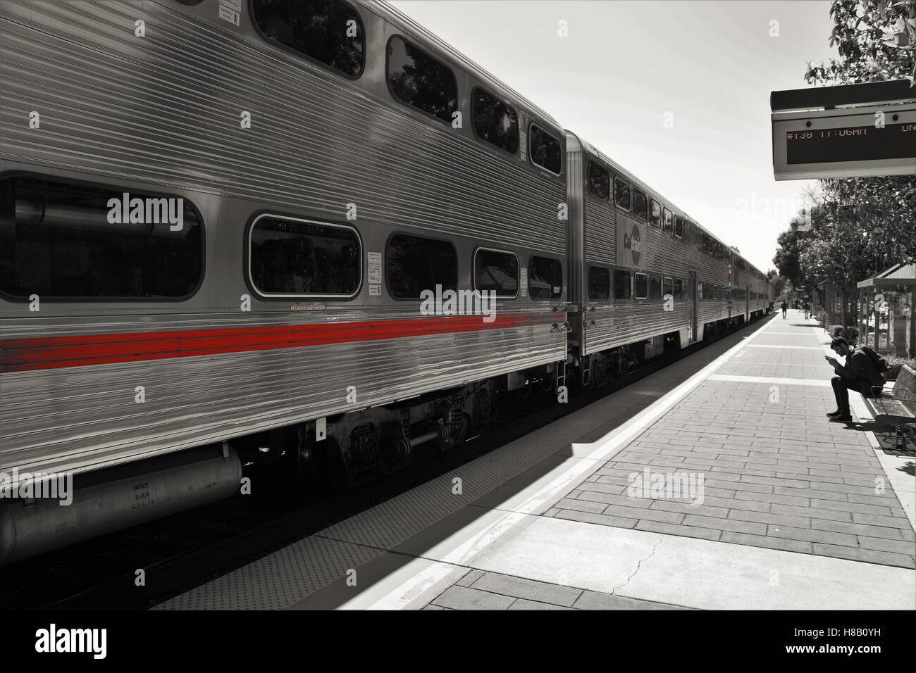 Treno lungo con striscia rossa in corrispondenza della piattaforma in bianco e nero Foto Stock