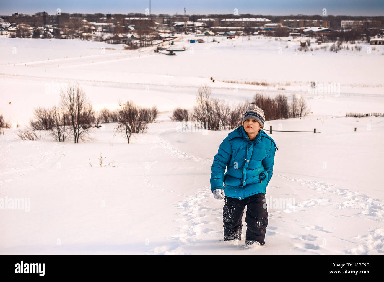 Giovane ragazzo in inverno fino alla collina sulle rive del fiume Foto Stock