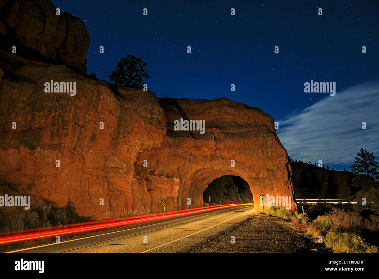 Un auto della striatura luci attraverso un piccolo tunnel in un rosso roccia affiorante sulla Scenic Byway 12 in rosso Canyon vicino a Panguitch USA Utah Foto Stock