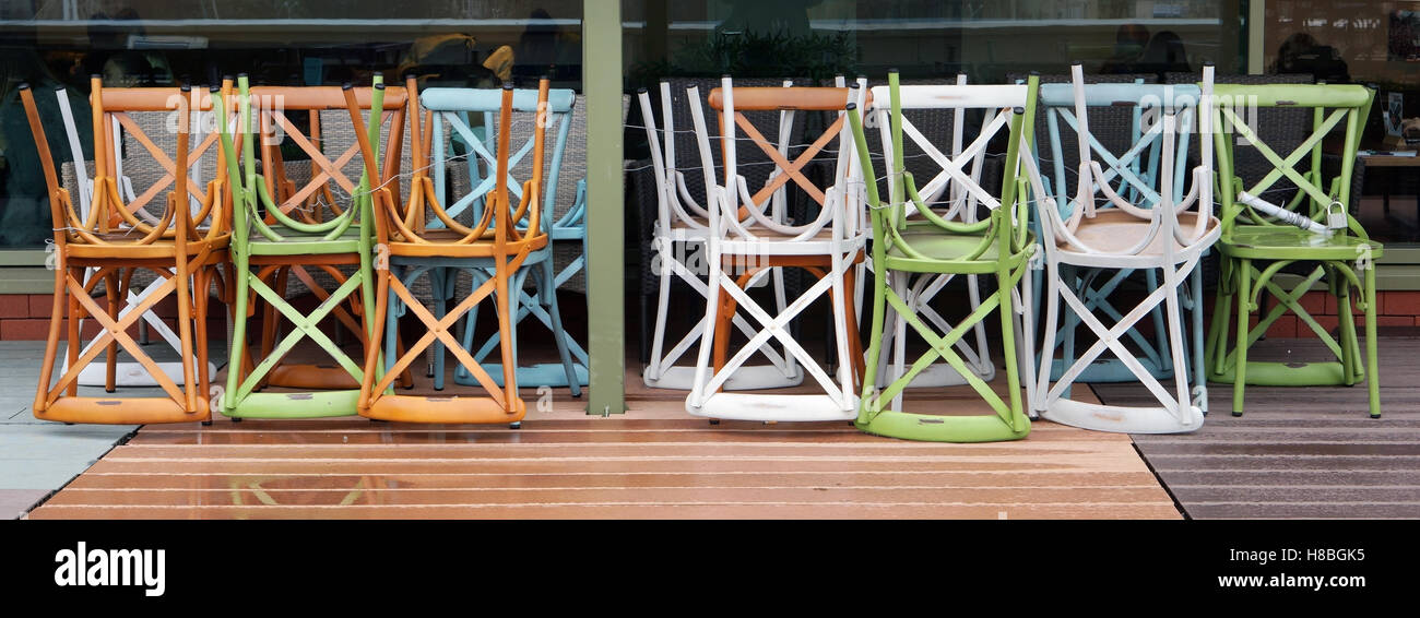 La street cafe è chiuso a causa di un autunno pioggia concetto. Sedie di colore vengono impilati e avvolto da un filo. Foto Stock