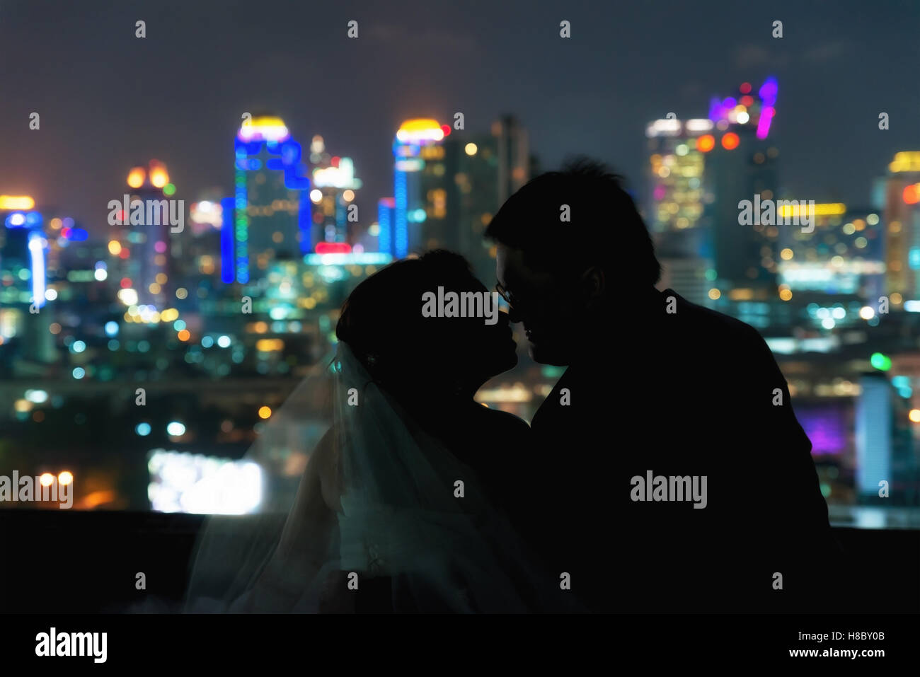 Silhouette di Asian giovane nozze di romanticismo momento sfocato notte oscura città centro di sfondo. Matrimonio amore di san valentino sto Foto Stock