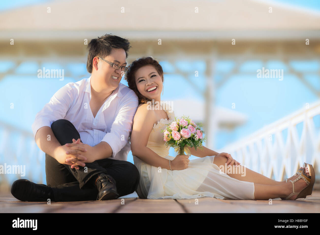 Ritratto di Allegro sposi abbracciando e guardando la telecamera. Asian sposi in ponte vicino al mare. Foto Stock