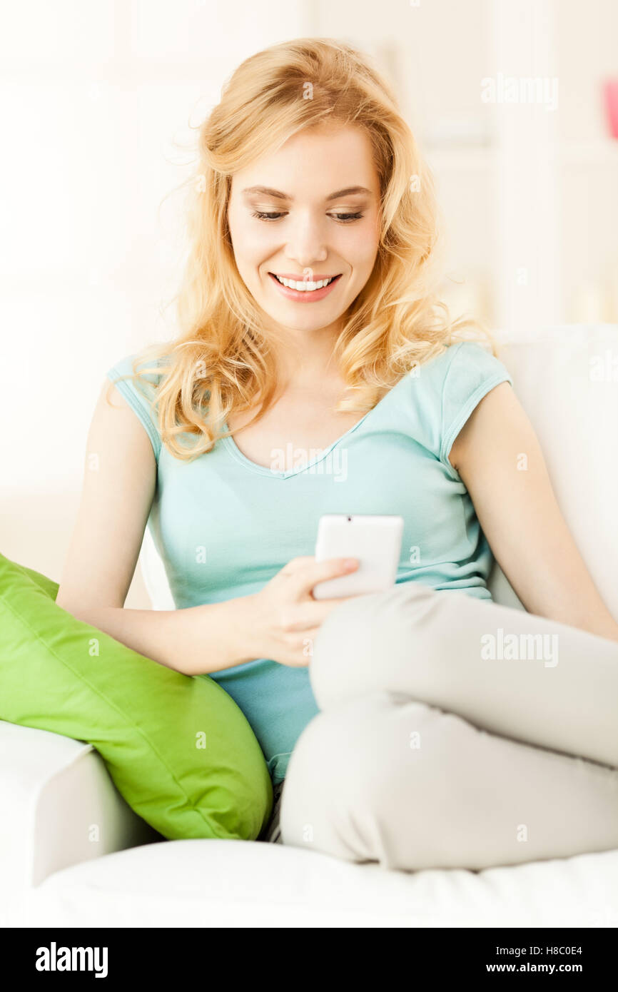 Sorridente giovane donna l'invio di messaggi di testo. Foto Stock