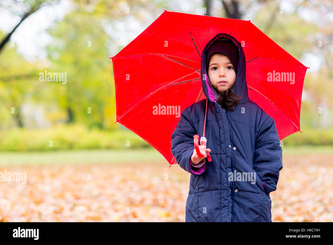 Bambina sotto ombrellone in autunno park Foto Stock