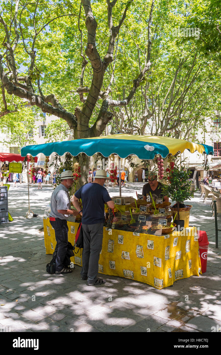La gente ad una produzione locale di mercato in stallo Place aux Herbes nel borgo medievale di Uzès, Gard, Francia Foto Stock