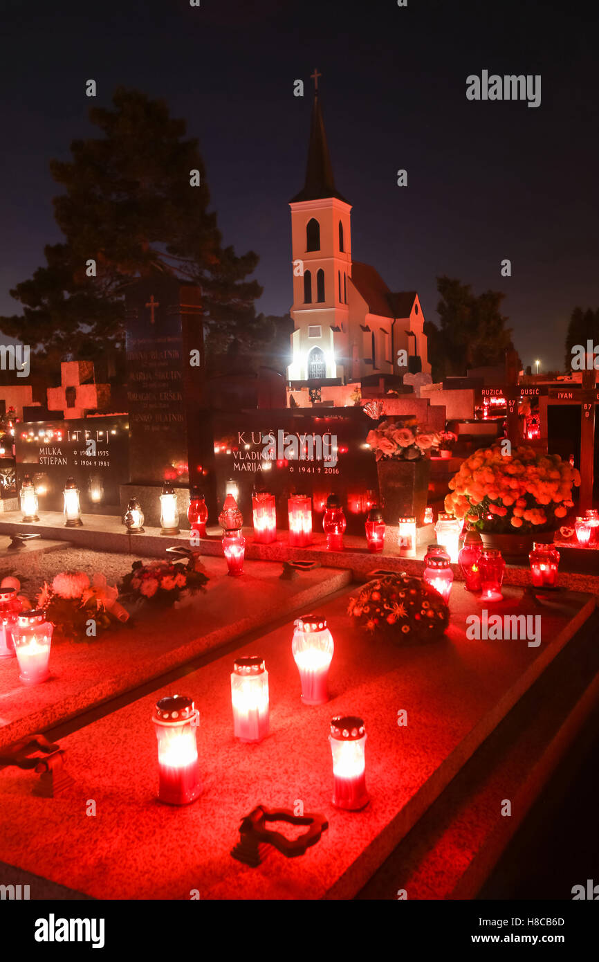 Una vista notturna di tombe ornate con ardente lampions con una chiesa in background sul giorno di Tutti i Santi nella Velika Gorica, Croazia Foto Stock