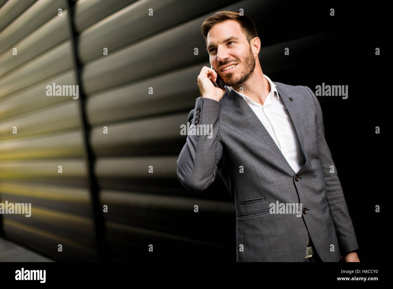 Imprenditore con un telefono dal muro nero Foto Stock
